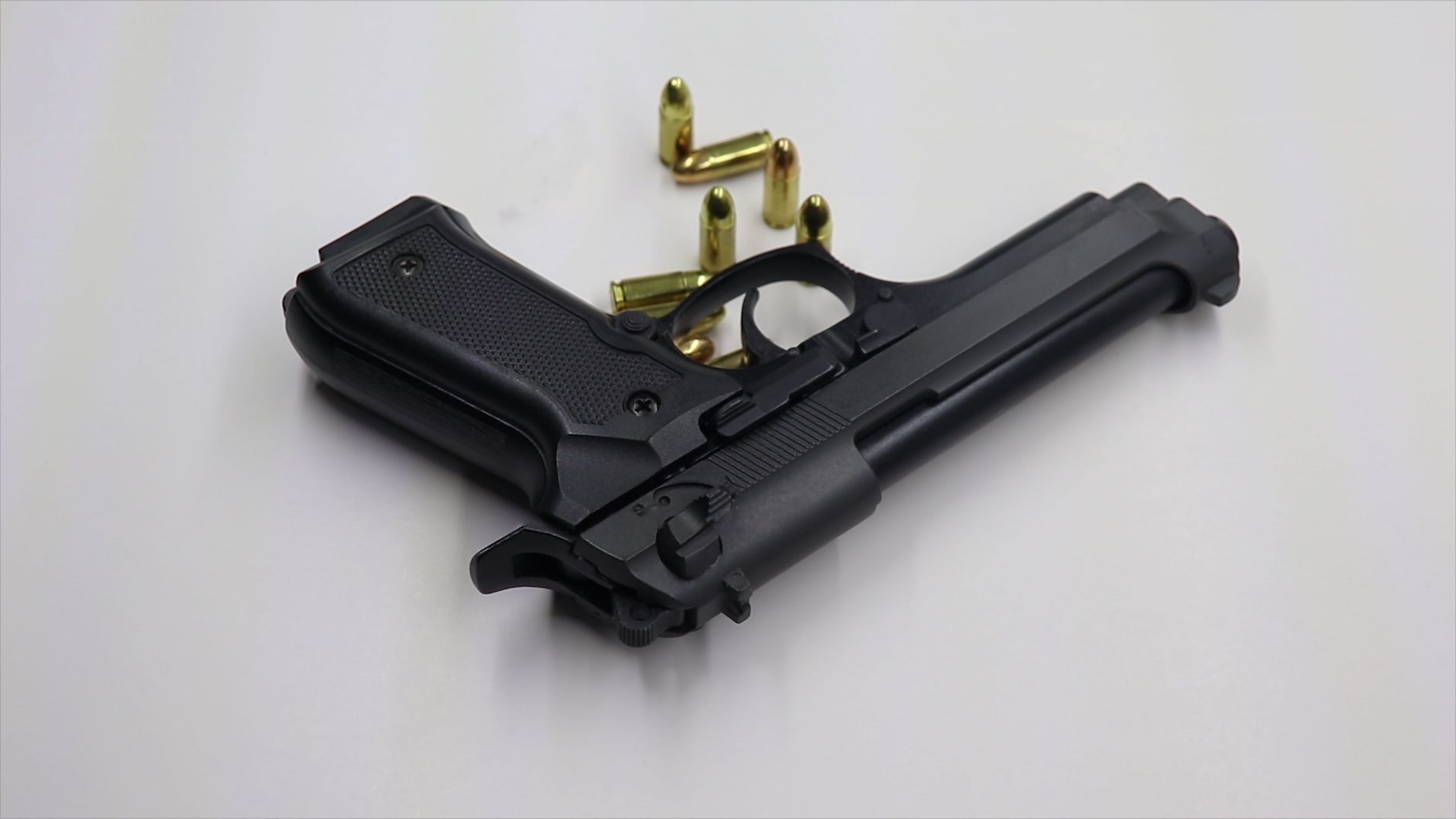 Czarny pistolet i rozsypane naboje na białym tle treningowym