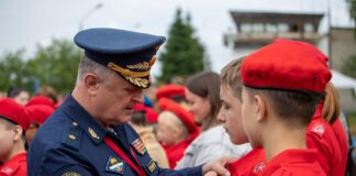 Rosyjski oficer przypina odznakę młodemu rekrutowi podczas ceremonii