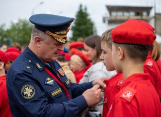 Rosyjski oficer przypina odznakę młodemu rekrutowi podczas ceremonii