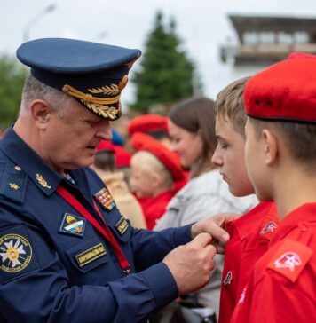 Rosyjski oficer przypina odznakę młodemu rekrutowi podczas ceremonii