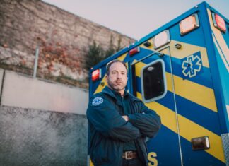Nocny dyżur ratownika medycznego w karetce S: jak wyglądają interwencje, emocje i powrót do domu po ciężkiej zmianie Ratownik medyczny stoi obok niebiesko-żółtej karetki na zewnątrz