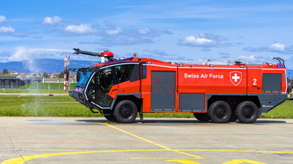 Wóz straży pożarnej Swiss Air Force polewa pas startowy w Payerne